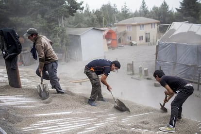 Vecinos de Ensenada limpian el tejado de una vivienda para evitar que el peso de las cenizas derrumbe la casa.