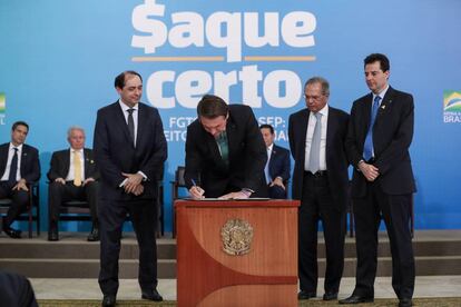 El presidente Jair Bolsonaro en el centro, en el acto de presentación del cambio en las reglas de retirada de fondos de reserva de los trabajadores.