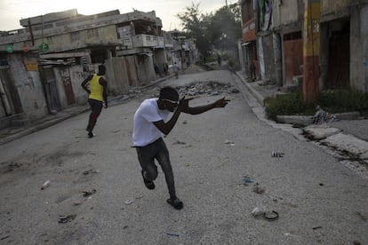 Un pandillero apunta con un arma imaginaria a un rival en una esquina que sirve como divisor entre territorios controlados por pandillas, en el barrio de Bel Air de Port-au-Prince, Haití.