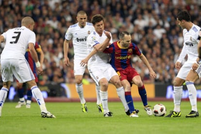 Iniesta intenta controlar el balón rodeado de jugadores del Madrid.