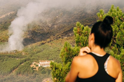 Una mujer observa la columna de humo junto a la urbanización El Picadero, de Pedro Bernardo (Ávila), que tuvo que ser desalojada de manera preventiva por la cercanía de las llamas del incendio, que parece controlado, declarado en Santa Cruz del Valle. 