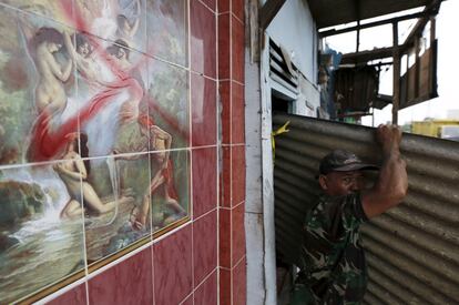 Un hombre saca una chapa de un prostíbulo antes de su demolición en el distrito rojo de Kaljdo en Yakarta (Indonesia).