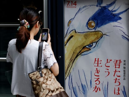 Una mujer toma una fotografía del póster de la nueva película de Miyazaki en un cine en Tokio el 14 de julio de 2023.