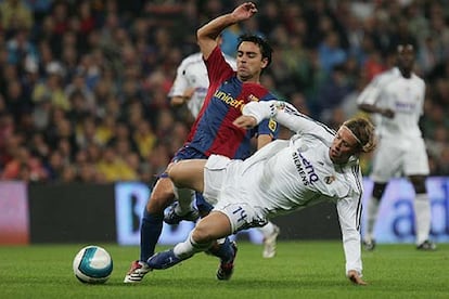 Guti cae mientras Xavi le intenta robar la pelota por la espalda.