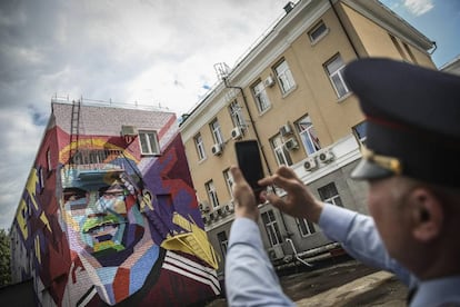 Un guarda de seguridad fotografía un graffiti del delantero de la selección portuguesa Cristiano Ronaldo en la fachada de un edificio Kazan (Rusia). Portugal se enfrenta a México en su primer partido de la Copa Confederaciones el próximo 18 de junio.