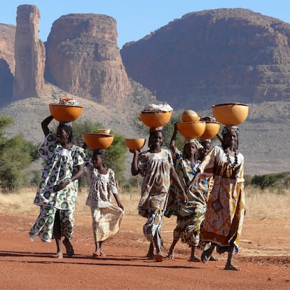 Mujeres de la tribu peul en Mali portan sobre sus cabezas grandes cuencos con ropa y leche. Peul, Mali, 2009