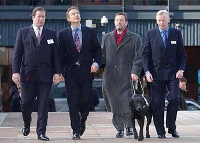 Tony Blair (segundo por la izquierda) y el ministro del Interior británico, David Blunkett (tercero por la izquierda, guiado por un perro lazarillo), junto a otros dos mandos policiales, ayer en Londres.