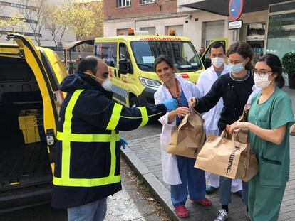 Un trabajador voluntario de Correos entrega comida a varios sanitarios de Madrid.