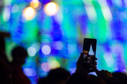 Cientos de turistas asistieron al encendido de las luces en el centro de Madrid. En la foto, un espectador graba con su móvil el espectáculo en la Puerta del Sol.