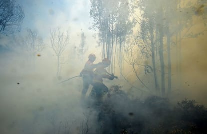 Dos bomberos usan una manguera para combatir un incendio forestal en Vale da Ponte.