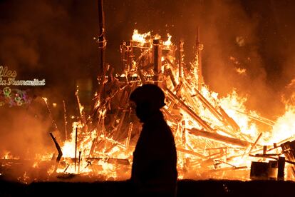 Una persona pasa cerca del fuego durante la Cremà de la falla del Ayuntamiento de Valencia.