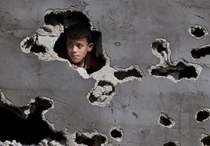 Un niño palestino mira a través de los boquetes realizados por los tanques israelíes en su casa de Rafá (Gaza).