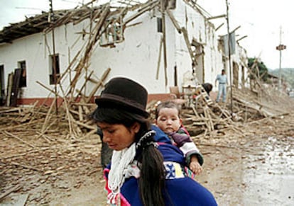Una indígena colombiana camina con su hija  frente a una casa destruida por la guerrilla en Silvia, provincia de Cauca.