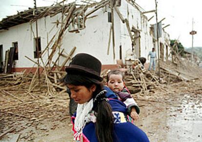 Una indígena colombiana camina con su hija  frente a una casa destruida por la guerrilla en Silvia, provincia de Cauca.