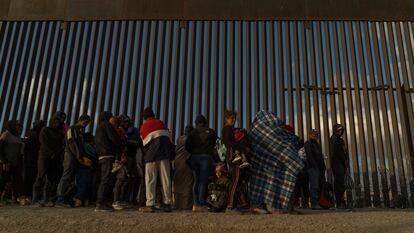 Migrants line up against the border wall to surrender to immigration officials after breaching a razor wire-laden fence along the bank of the Rio Grande in El Paso, Texas, U.S., March 25, 2024.