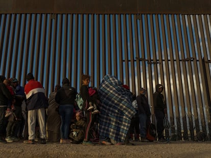 Migrants line up against the border wall to surrender to immigration officials after breaching a razor wire-laden fence along the bank of the Rio Grande in El Paso, Texas, U.S., March 25, 2024.