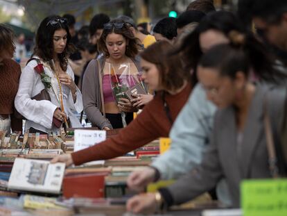 Dos jóvenes miran libros mientras sostienen rosas en la de plaza Catalunya.