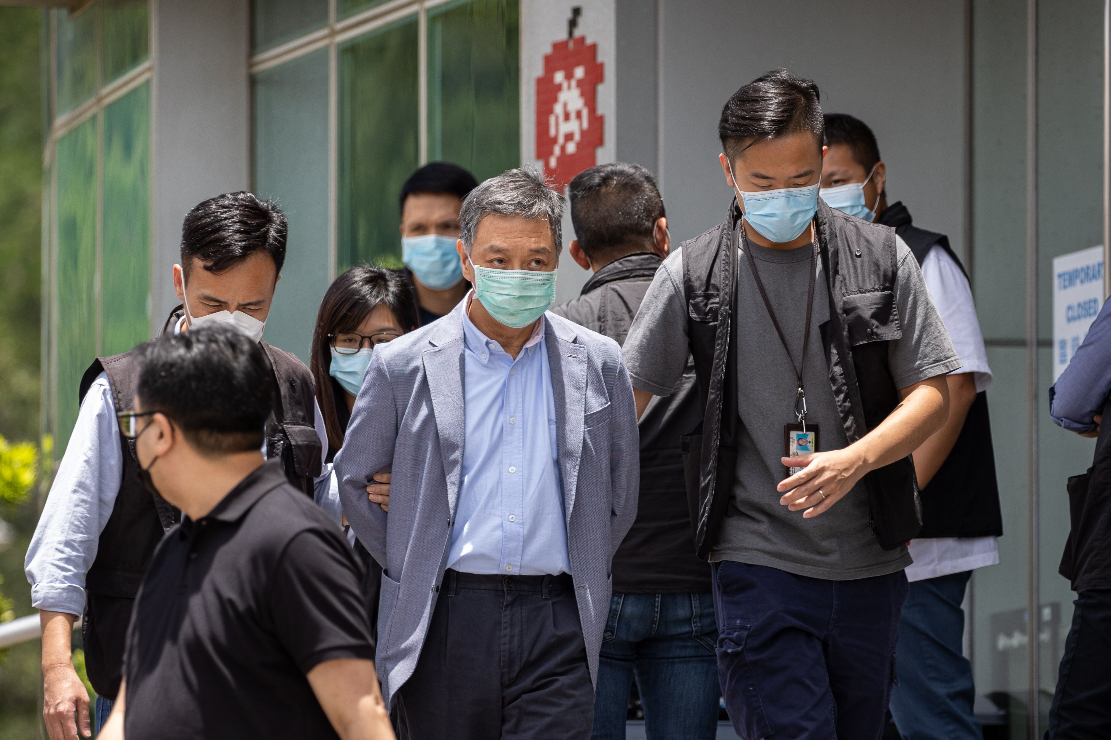El director de operaciones del Apple Daily, Royston Chow Tat Kuen (centro), es escoltado por agentes de policía al salir de la oficina de Next Media, editor del Apple Daily, en Hong Kong (China), este jueves.
