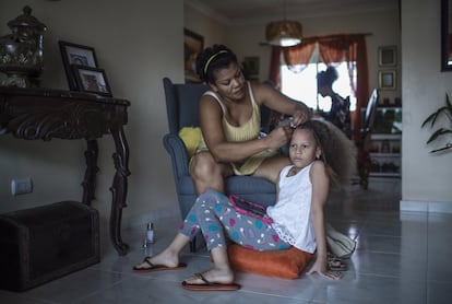 <p>María Pérez, de 36 años, peina a su hija Abril en el salón de su casa en la ciudad de Santo Domingo durante el confinamiento. Pérez tiene dos hijas de nueve (Abril) y 14 años y es maestra suplente.</p>  <p>Cuando empezó la pandemia era estudiante de último curso de la carrera de Psicología. Durante la cuarentena compaginó sus estudios con el trabajo de la casa y el cuidado de sus hijas. También ayudaba a las niñas en las tareas escolares, algo que, con el cierre de las escuelas, supuso un esfuerzo añadido que en la mayor parte de las casas recayó sobre las mujeres. Pérez contaba que el confinamiento fue una oportunidad para hablar con su esposo de la necesidad de la corresponsabilidad en el hogar. </p>  <p>A nivel mundial, las mujeres realizan el 76% del total de horas de trabajo de cuidado no remunerado, según la Organización Internacional del Trabajo (OIT). Según los datos del Informe de Caracterización del Mercado Laboral Dominicano efectuado por la Iniciativa de Paridad de Género en República Dominicana, se estima que las mujeres dominicanas dedican cinco veces más tiempo que los hombres a la labor de cuidados y 3,5 veces más tiempo que ellos al trabajo doméstico no remunerado. </p>