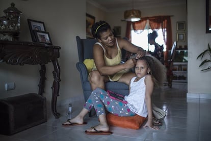 <p>María Pérez, de 36 años, peina a su hija Abril en el salón de su casa en la ciudad de Santo Domingo durante el confinamiento. Pérez tiene dos hijas de nueve (Abril) y 14 años y es maestra suplente.</p> <p>Cuando empezó la pandemia era estudiante de último curso de la carrera de Psicología. Durante la cuarentena compaginó sus estudios con el trabajo de la casa y el cuidado de sus hijas. También ayudaba a las niñas en las tareas escolares, algo que, con el cierre de las escuelas, supuso un esfuerzo añadido que en la mayor parte de las casas recayó sobre las mujeres. Pérez contaba que el confinamiento fue una oportunidad para hablar con su esposo de la necesidad de la corresponsabilidad en el hogar. </p> <p>A nivel mundial, las mujeres realizan el 76% del total de horas de trabajo de cuidado no remunerado, según la Organización Internacional del Trabajo (OIT). Según los datos del Informe de Caracterización del Mercado Laboral Dominicano efectuado por la Iniciativa de Paridad de Género en República Dominicana, se estima que las mujeres dominicanas dedican cinco veces más tiempo que los hombres a la labor de cuidados y 3,5 veces más tiempo que ellos al trabajo doméstico no remunerado. </p>