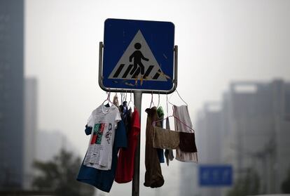 Ropa procedente de una lavandería, colgada en una señal de tráfico, en una calle de Pekín (China).