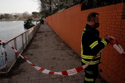 Un bombero acordona una zona mientras algunos de sus compañeros trabajan para retirar un árbol caído en la Casa de Campo.