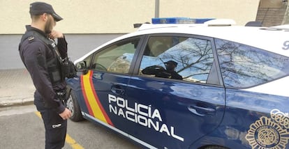 Un agente de la Policía Nacional, junto a un vehículo policial.