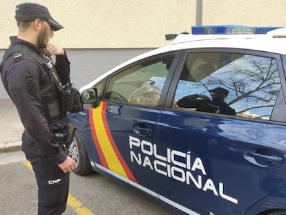 Un agente de la Policía Nacional, junto a un vehículo policial.