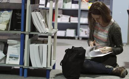 Una chica se sienta en el suelo para leer un libro en una librería.