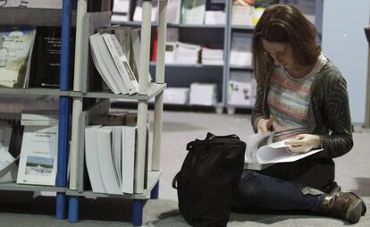 Una chica se sienta en el suelo para leer un libro en una librer&iacute;a. 