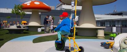 Un niño pasea con un 'kiciclo' por el jardín de la azotea del Hospital La Paz, en Madrid.