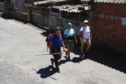 Peregrinos pasan junto a un tramo descuidado del Camino de Santiago en Palas de Rei (Lugo).