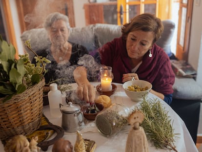 Pepa Amaya (a la izquierda) quema incienso junto a algunas de las hierbas con las que elabora un alcohol que regala como remedio natural. Junto a ella, su amiga María Jesús Fernández.