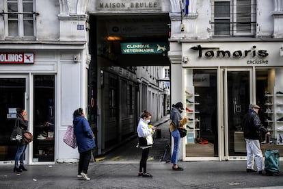 Clientes hacen cola para entrar en un supermercado de París guardando la distancia de seguridad