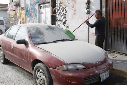 Un hombre limpia ceniza de su auto hoy, 18 de abril de 2016, producto de la erupción del volcán Popocatépetl en el estado de Puebla (México)