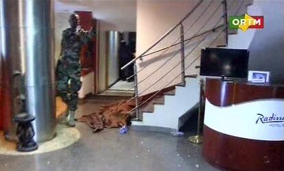 En la imagen, de la cadena ORTM, un militar maliense pasa ante un cadáver cubierto por una sábana en el interior del hotel.