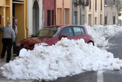 Vecinos de La Bisbal d'Empord observan la nieve acumulada en la puerta de sus casas.