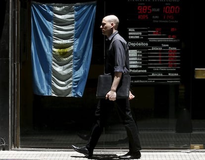 Un hombre pasa junto a pantalla que muestra el tipo de cambio en el distrito financiero de Buenos Aires.