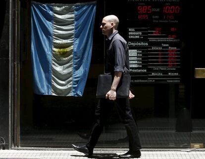 Un hombre pasa junto a pantalla que muestra el tipo de cambio en el distrito financiero de Buenos Aires.