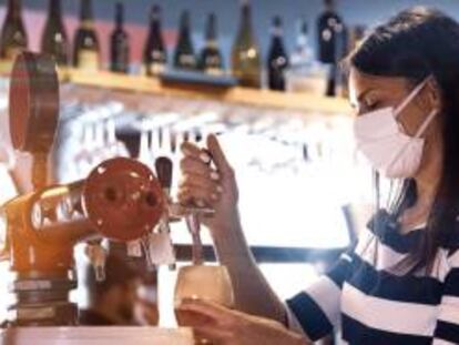 Una camarera sirve una cerveza en un bar.