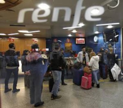 Varios viajeros esperan en la estación de tren de Atocha, en Madrid.