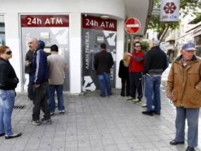 Un grupo de personas hace cola junto al cajero automático de una sucursal cerrada del banco Laiki, en Nicosia.