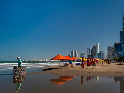 Turistas y un vendedor caminan en una de las playas de Cartagena (Colombia), en una imagen de archivo.