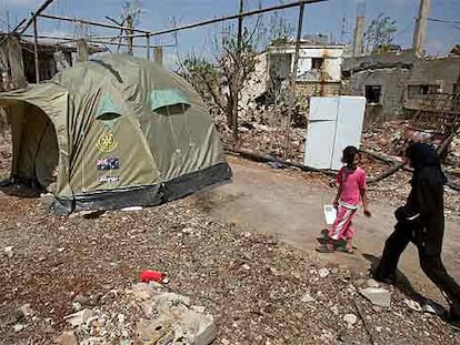 Dos niñas libanesas caminan junto a una tienda de campaña en Qana (sur de Líbano), una de las localidades más devastadas por los bombardeos.