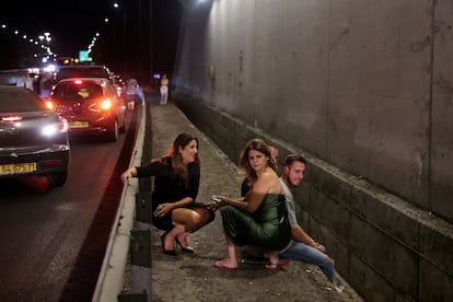 Un grupo de personas se refugia en los márgenes de una carretera en el centro de Israel durante el ataque lanzado por Irán. 