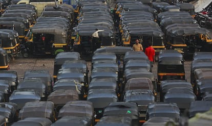 Unos conductores de 'rickshaw' (vehículo pequeño de dos ruedas tirado por un hombre en bicicleta que se utiliza en los países asiáticos) charlan en un aparcamiento antes de comenzar la jornada laboral en Bombay (India).