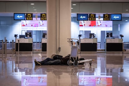 Un hombre sin techo duerme en la zona intermodal de la Terminal 1 del aeropuerto de Barcelona-El Prat con un respirador enchufado.