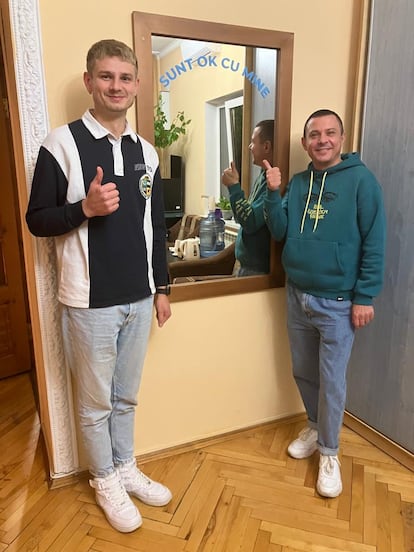 Slava Mulear (derecha) y Cristian Rotari (izquierda), posan junto a un espejo en el que se lee "Estoy bien conmigo mismo", en la sede de la ONG moldava Genderdoc, que defiende los derechos de la comunidad LGTBI, el 8 de noviembre de 2023.