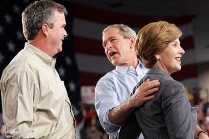 El presidente Bush (centro), abrazado a su esposa, Laura, conversa con su hermano, el gobernador de Florida, Jeb Bush, ayer en Coconut Grove.