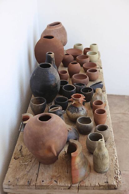 Piezas de cerámica, algunas horneadas, otras todavía no, con tonalidades que van de cobres y dorados a grises y negros.